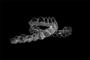 Two clear aligners arranged against dark background