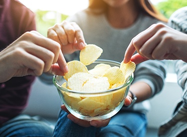 Teen friends with Invisalign sharing a bowl of chips