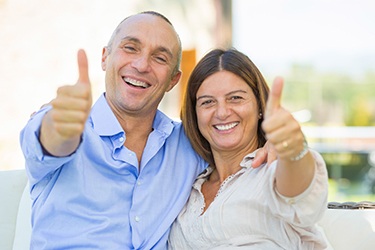 Older couple smiling giving the thumbs up