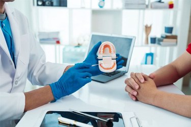 Dentist and patient sitting at desk during consultation