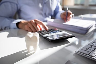 Man using calculator to budget for the cost of cosmetic dentistry in Schenectady