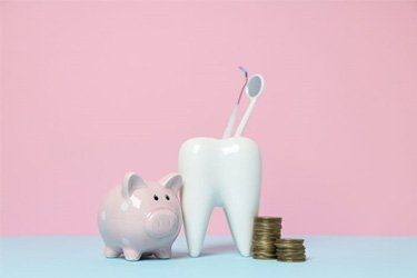 Tooth model next to piggy bank and coins