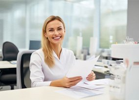 Smiling dental team member sitting behind desk