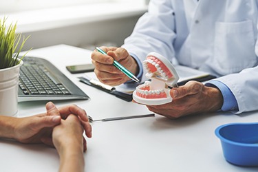 Close-up of dentist speaking with a patient about denture stabilization using dental implants