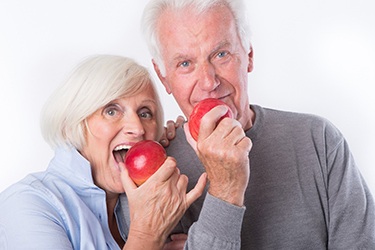 Senior couple enjoying fresh fruit with help of stabilized dentures