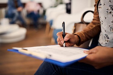 Dental patient filling out form on clipboard