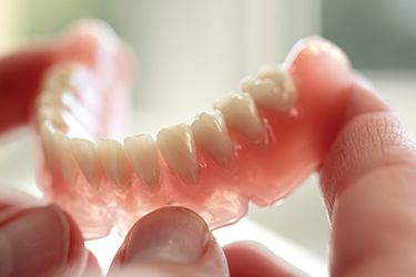 Hands holding full denture prosthetic