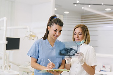 Dental team looking at X-Ray, comparing treatment options for patient