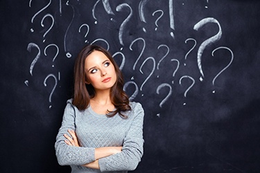 Woman in gray sweater, thinking about questions about emergency dentistry