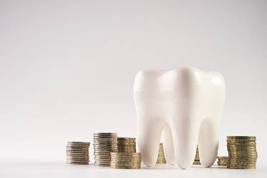 Tooth model next to stacks of coins