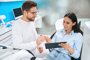 Dental patient in treatment chair, holding clipboard