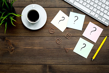 Sticky notes with question marks on computer desk