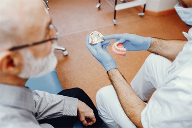 Dentist using model to explain implant denture procedure?