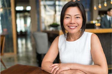 Smiling woman in café with dental implants in Schenectady