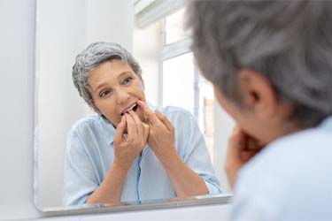 Woman flossing her dental implants in Schenectady