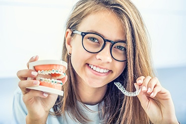 Girl holding Invisalign and tooth model with braces