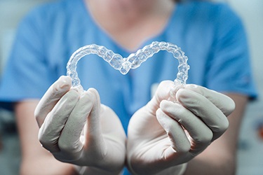 Dental professionals holding Invisalign aligner in heart shape