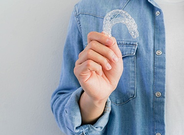 Young man holding two aligners for Invisalign Teen