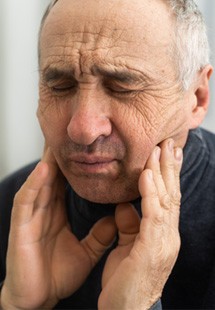 Man rubbing jaw looking uncomfortable