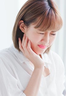 Woman holding a glass of water in pain while holding jaw