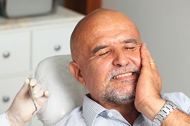 Older male patient holding cheek