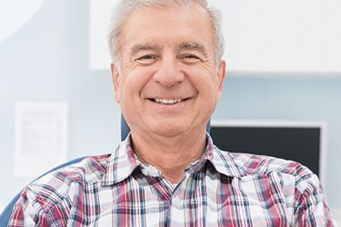 Older smiling man in dental chair