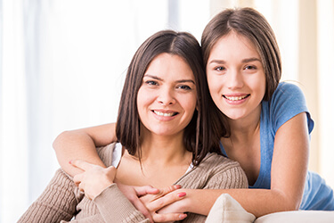 Smiling mother and daughter with healthy teeth