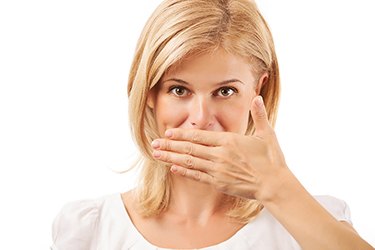 Blond woman hiding mouth, embarrassed by crooked teeth