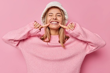 Woman in pink sweater pointing at her teeth