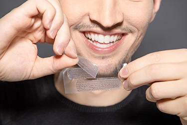 Man preparing to apply whitening strip to his teeth