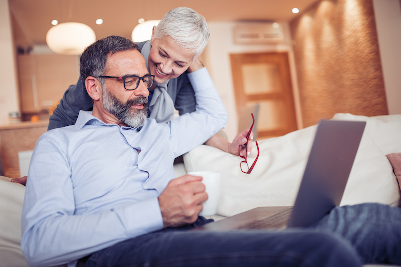 Happy mature couple using laptop in the living room.