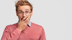 Man covering his mouth, wearing shocked expression 