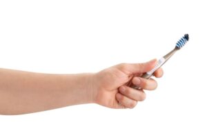 Hand holding toothbrush against white background 