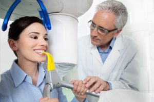 Dentist positioning female patient inside cone beam scanner