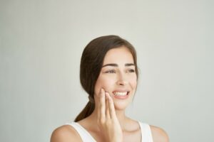 Grimacing woman touching the side of her face