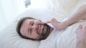 Man in bed, suffering with a toothache