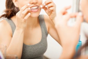 Woman applying whitening strip in front of mirror