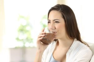 Woman sipping on chocolate drink after All-on-4 surgery