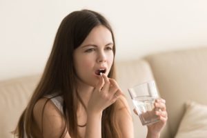 Woman taking sedative pill before dental appointment