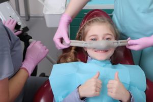 Young girl giving two thumbs up for nitrous oxide sedation dentistry